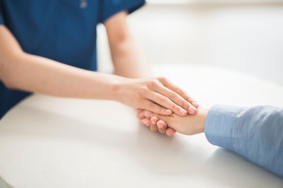 患者さんの手を握るスタッフ